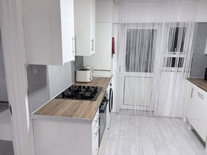 Een moderne keuken met een houten aanrecht, een gasfornuis en witte kastjes.