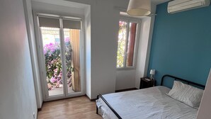 Ein Schlafzimmer mit Bett, Fenster, Deckenventilator und Blick auf einen Garten.