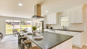 A modern kitchen with a large island, white cabinetry, and a view to the outdoors. - Northport Game Day Getaway: 5 Mi to University! (Northport)