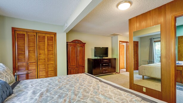 A bedroom with a bed, wooden wardrobe, a television, and a mirror. - Relax & Recharge: Edgewood Home w/ Balcony (Edgewood)