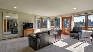 A spacious living room with a large sofa, a television, and a dining area with a glass table. - Relax & Recharge: Edgewood Home w/ Balcony (Edgewood)