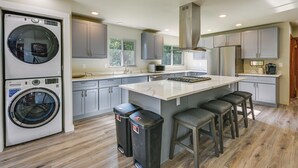 A modern kitchen with a built-in washer, a large island with bar stools, and a view of the outdoors through the window. - Relax & Recharge: Edgewood Home w/ Balcony (Edgewood)