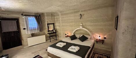 A bedroom with a bed, two bedside tables with lamps, a radiator, a window with curtains, a mirror, and a wall-mounted star decoration.