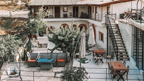 A building with a terrace, outdoor seating, and a staircase leading to an upper level. - TURAN Cappadocia Cave (Nevsehir)