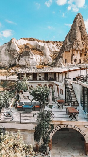 A building with a terrace, outdoor seating, and a staircase leading to an upper level. - TURAN Cappadocia Cave (Nevsehir)