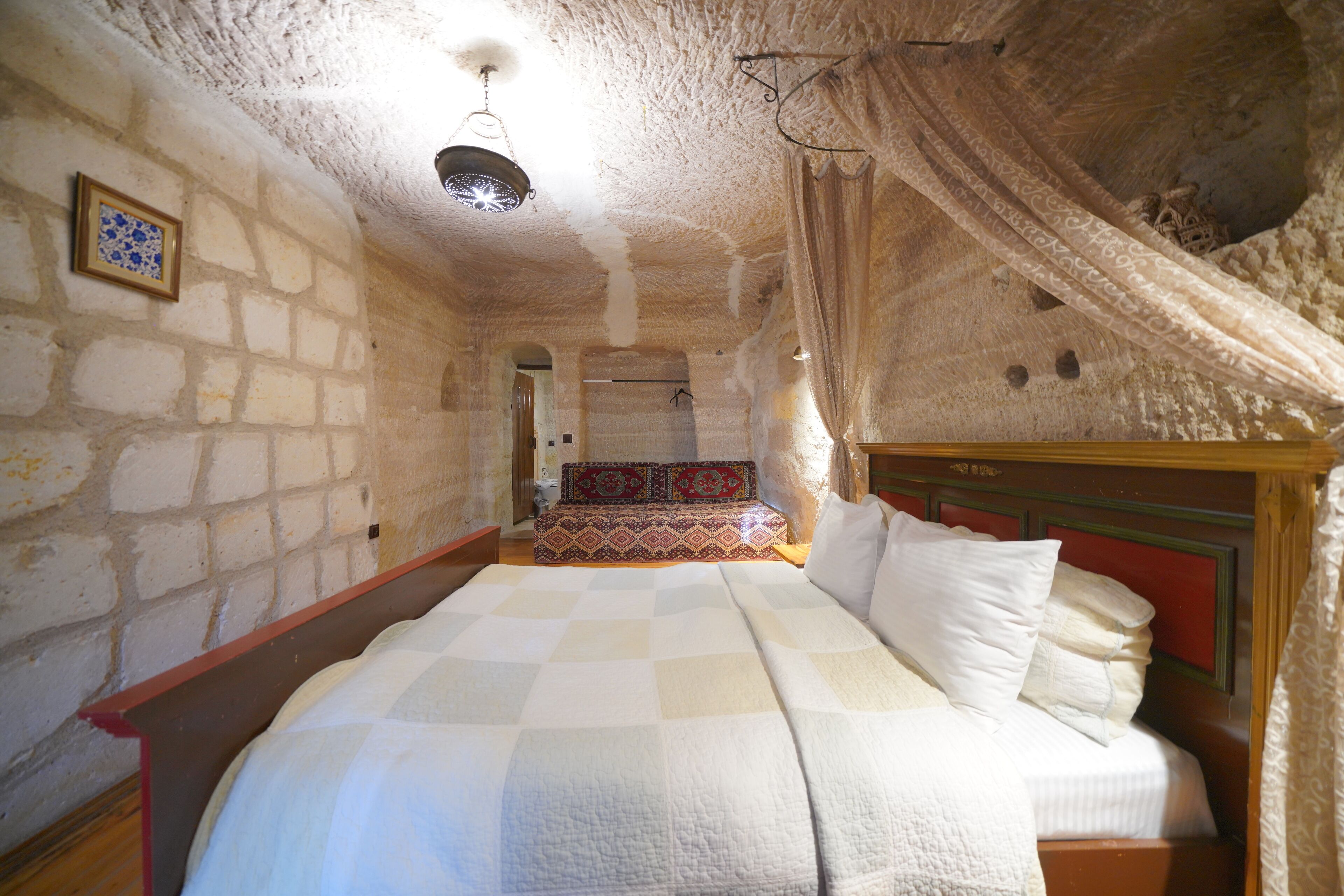 A bedroom with a large bed, a patterned rug, and a stone wall.