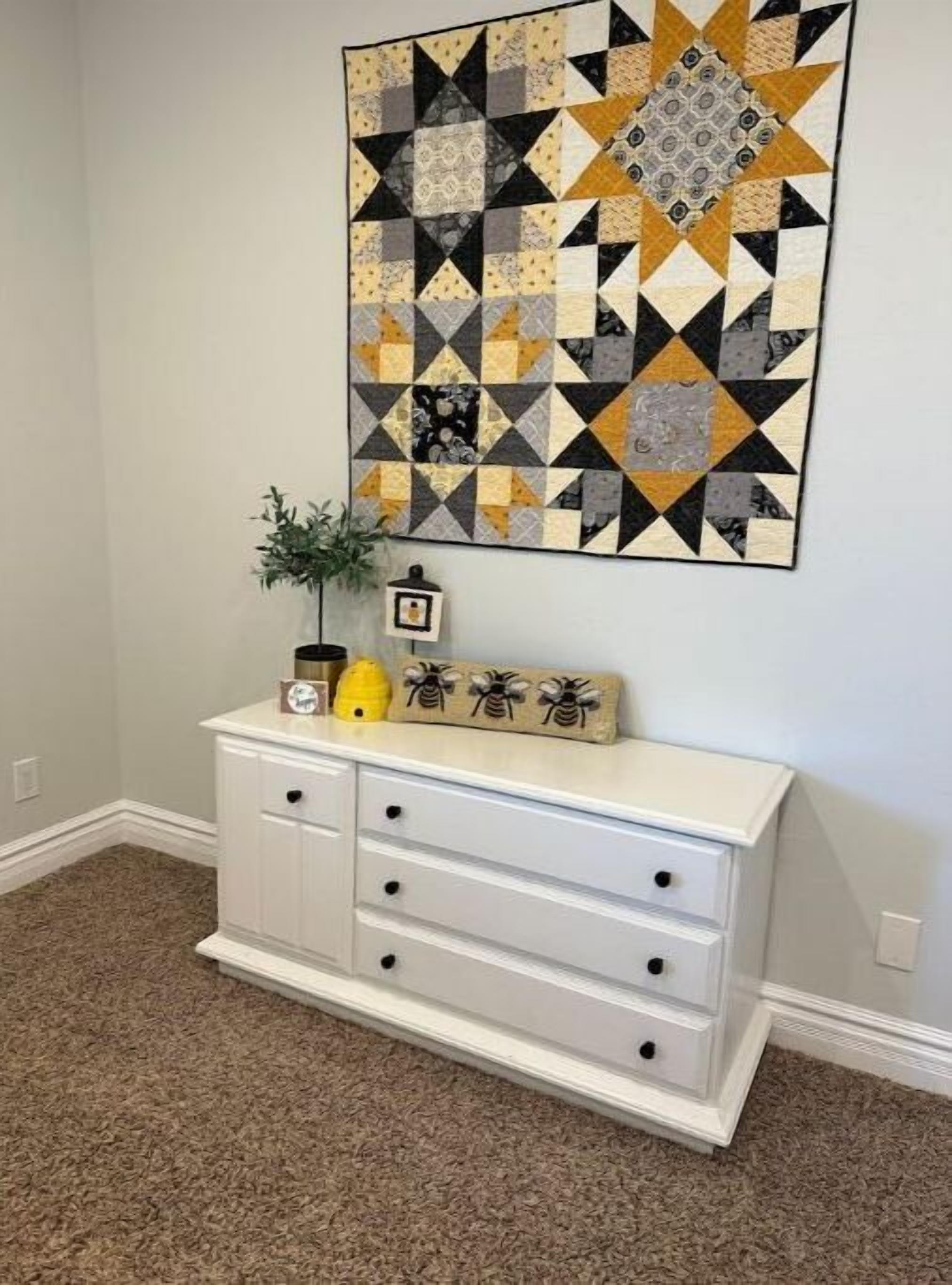 A room with a white dresser, a framed picture, and a small potted plant.