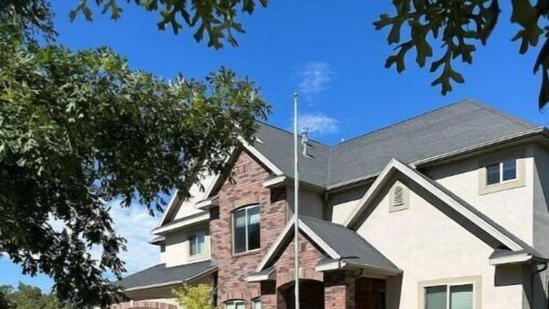 A two-story house with a garage, a driveway, and a well-maintained lawn.