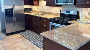 A modern kitchen with dark wooden cabinets, stainless steel appliances, and a granite countertop.