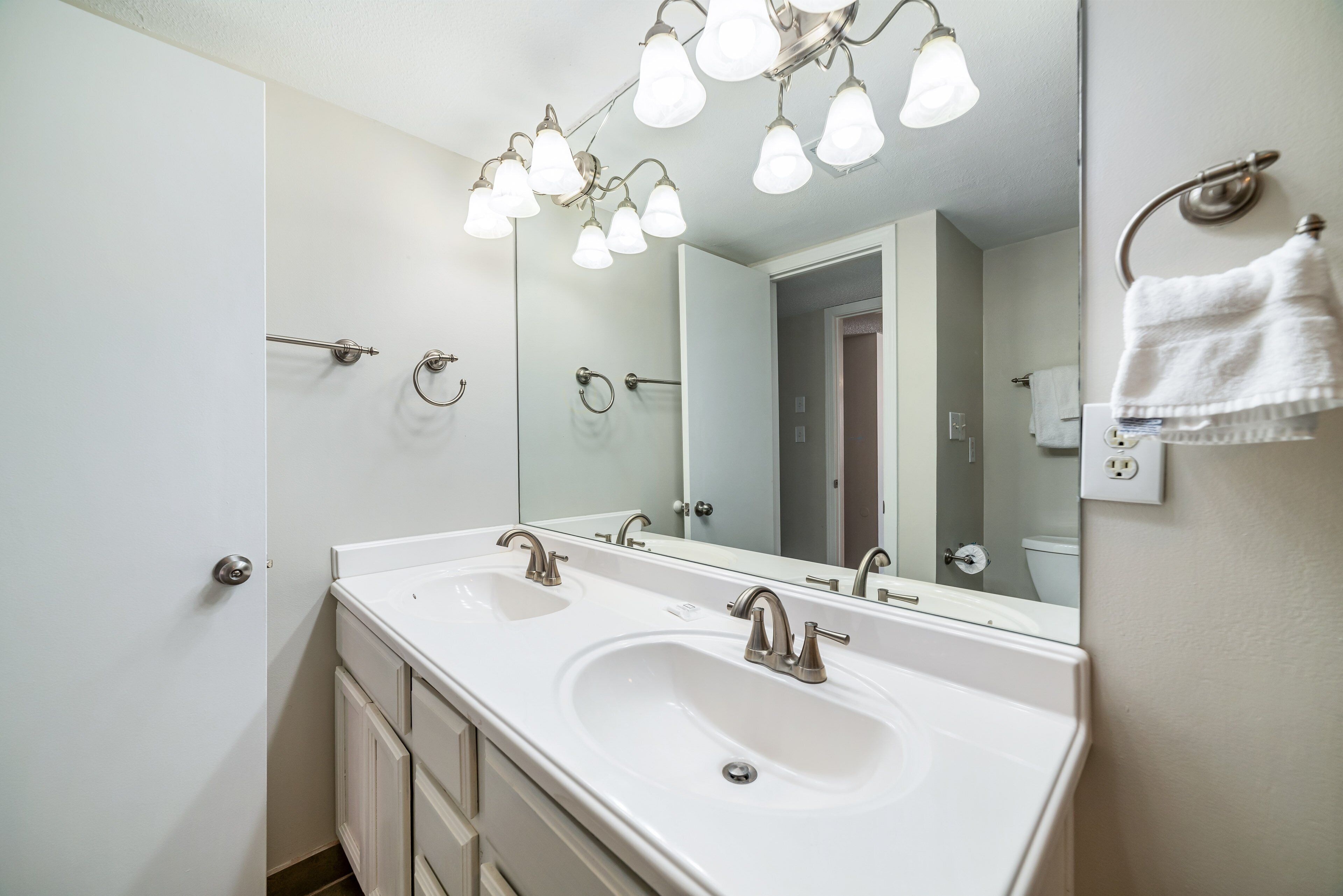 Une salle de bain avec deux lavabos, un grand miroir et un porte-serviettes.