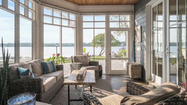A sunlit room with a large window overlooking a lake, furnished with a sofa, chairs, and a table. - The Luxury Lake Minnetonka Home, Hot Tub, Captain Services, 4 Bedrooms, on lake (Shorewood)