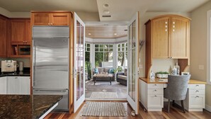 A modern kitchen with wooden cabinets, a stainless steel refrigerator, and a dining area with a sofa and coffee table. - The Luxury Lake Minnetonka Home, Hot Tub, Captain Services, 4 Bedrooms, on lake (Shorewood)