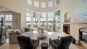 A spacious living room with a large window overlooking a lake, a fireplace, and a cozy seating area. - The Luxury Lake Minnetonka Home, Hot Tub, Captain Services, 4 Bedrooms, on lake (Shorewood)