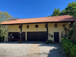 Un bâtiment doté d’un toit recouvert de tuiles, d’une cour pavée et d’un escalier menant à une porte.