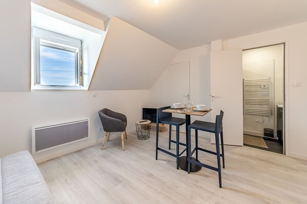 A modern, compact living space with a dining area, a chair, a radiator, and a view of the outdoors. - L'écrivain - Wifi - Saint-Serge (Angers)