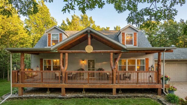 Une cabane en rondins à deux étages, dotée d’un porche couvert et d’une entrée principale.