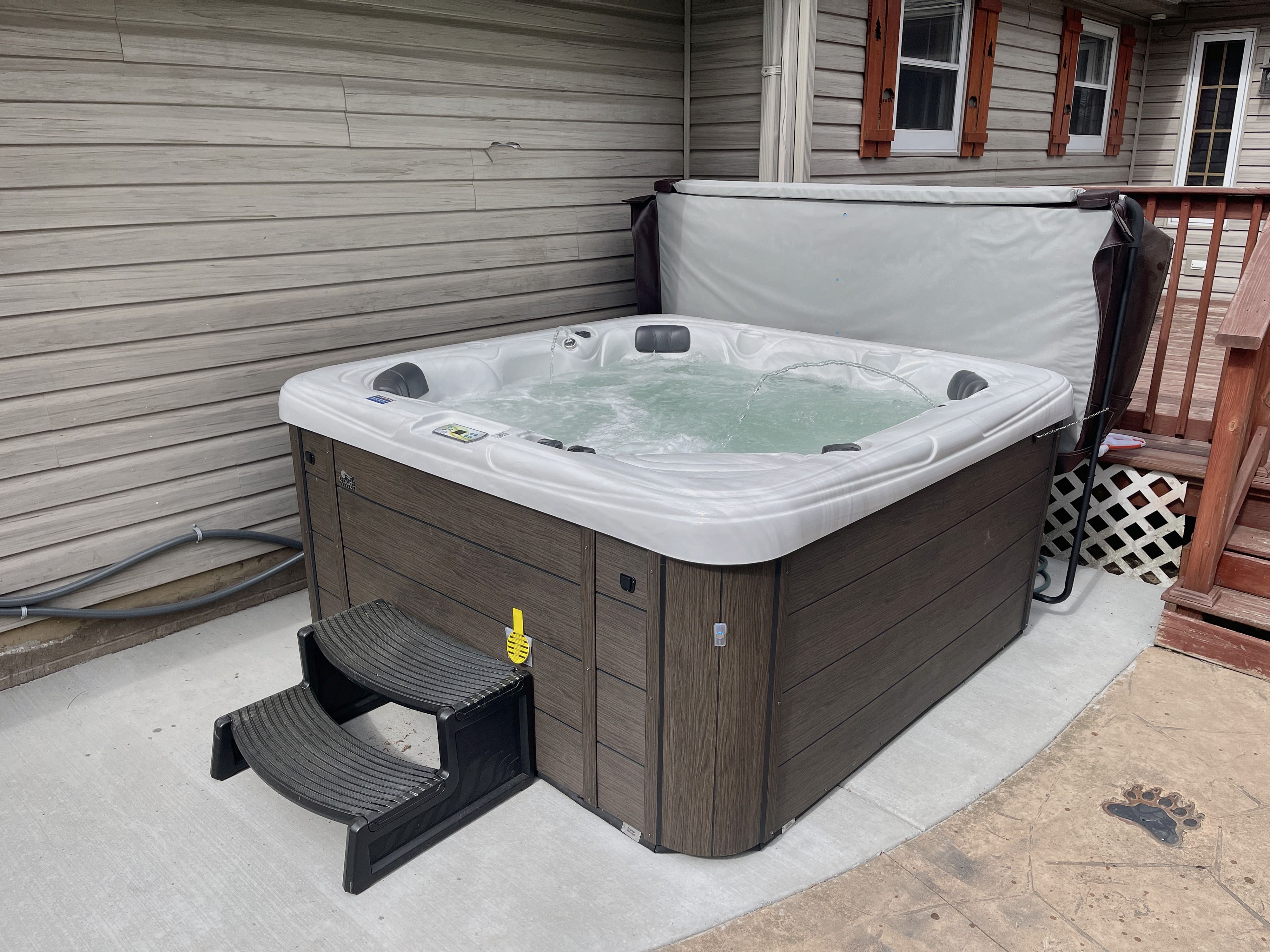 A hot tub with a wooden exterior, a step leading into it, and a covered area above.
