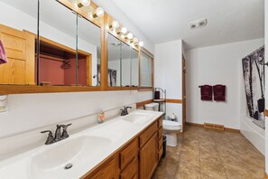 A bathroom with a large mirror, vanity with two sinks, a toilet, and a bathtub. - Dells Escape with Hot Tub Huge Game Room (Lyndon Station)