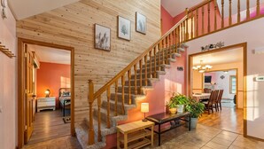 Un escalier avec des rampes en bois, un banc en bois, une table à manger avec des chaises et une plante en pot.