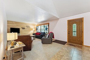 A living room with a sofa, armchair, and a television on a wooden wall. - Dells Escape with Hot Tub Huge Game Room (Lyndon Station)