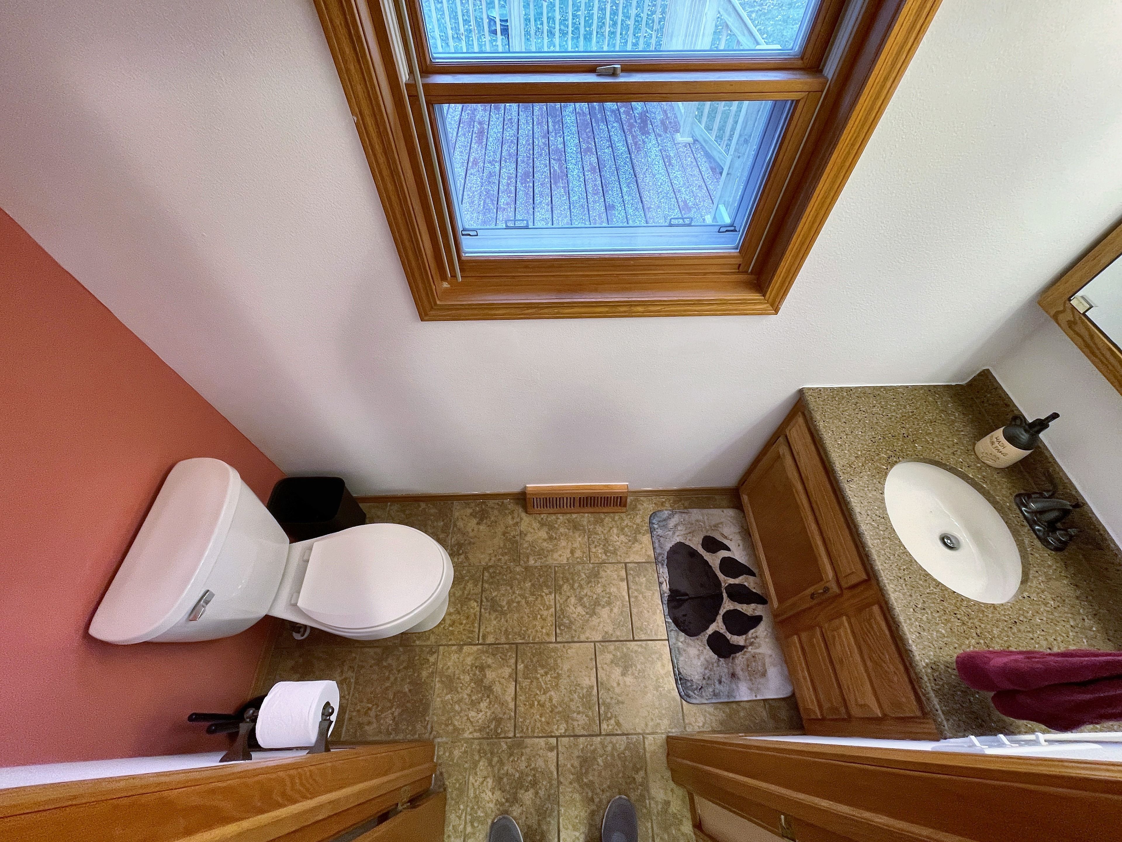 Bright bathroom with natural light, tiled floors, and warm wood vanity