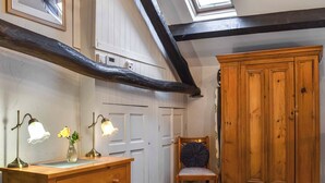 A room with a wooden dresser, a chair, a large wooden cabinet, a skylight, and a white door.