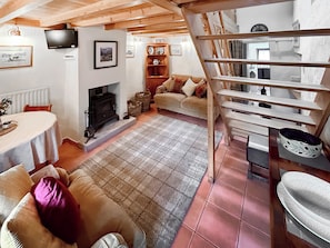 A cozy living room with a fireplace, a sofa, a dining table, and a staircase. - 1 bedroom accommodation in Ennerdale (Ennerdale)