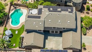 Una propietat residencial amb diversos edificis, panells solars, piscina i un jardí ben cuidat.