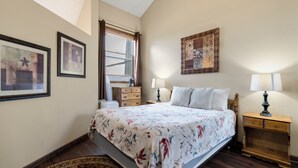 A bedroom with a bed, two bedside tables with lamps, a dresser, and framed artwork on the walls. - Valley View (Flagstaff)