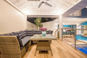 Relax in this spacious room with a sofa, glass table, and staircase leading to an upper level.