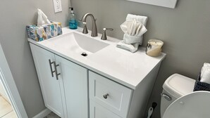 A bathroom with a white sink, a toilet, and a shower area. - Relax By The Sea With Infinity Ocean Views (Galveston)