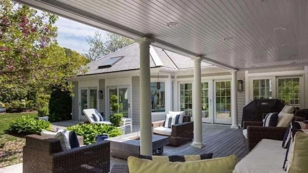 A covered outdoor patio area with wicker furniture, a barbecue grill, and a view of the house in the background. - Heated Indoor Pool and Spa - Golf Course View (Mashpee)