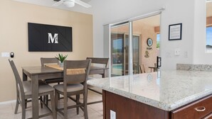 A modern kitchen with a granite countertop, a dining area with a table and chairs, and a ceiling fan. - STOCKED Pool Home, RV & Boat parking, Game room. Sleeps 13 (Lake Havasu City)