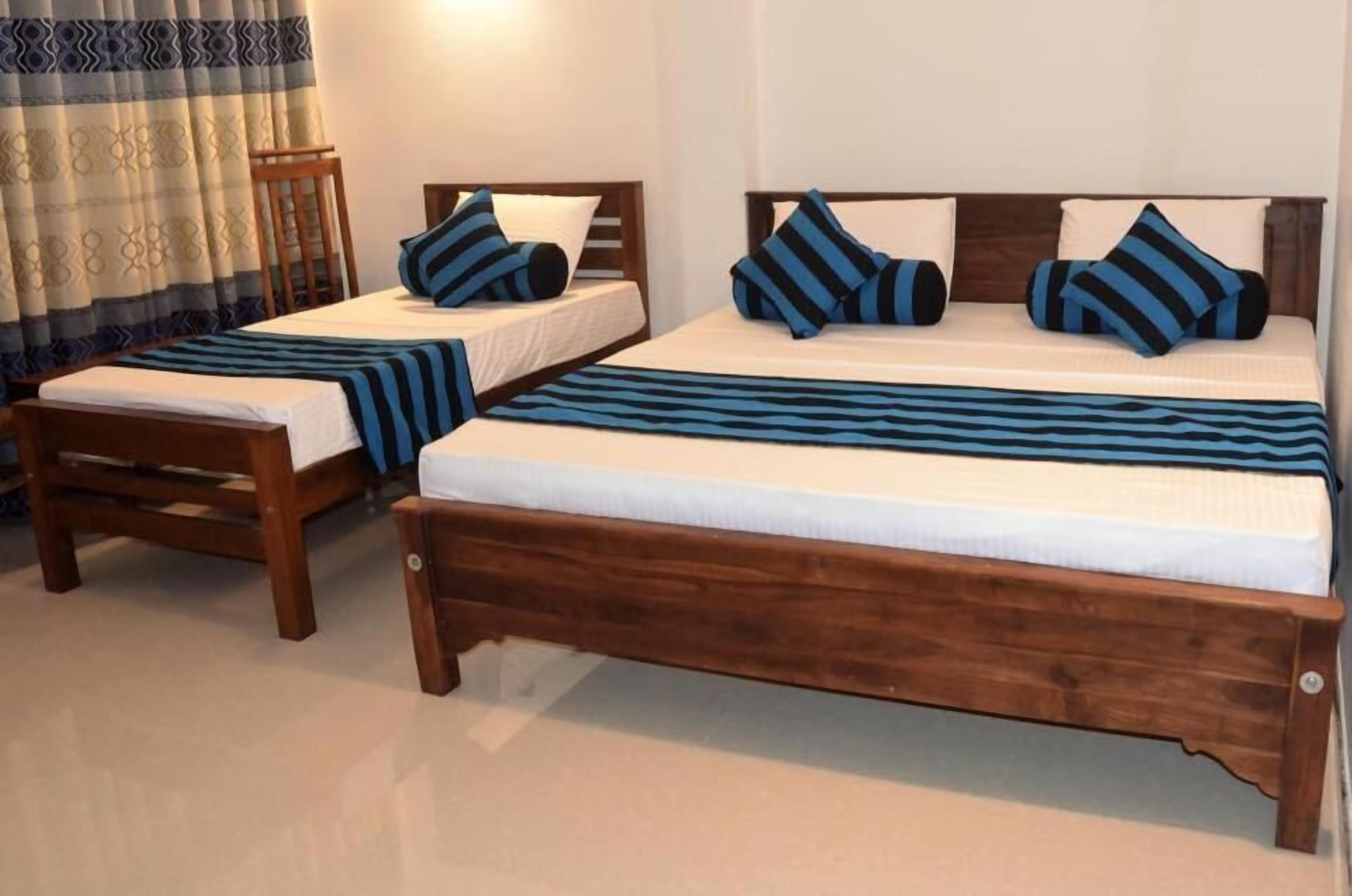 Two wooden beds with matching headboards and footboards, each with a white mattress and blue-striped bedding.