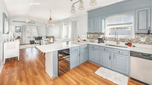 Une cuisine moderne avec des meubles bleu clair, un îlot central blanc et un plancher en bois.