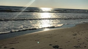 Une plage où la lumière du soleil se reflète sur l’eau et le sable.