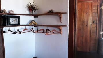 Een hoek met houten planken waarop een thermostaat, een decoratief object en een plant staan.