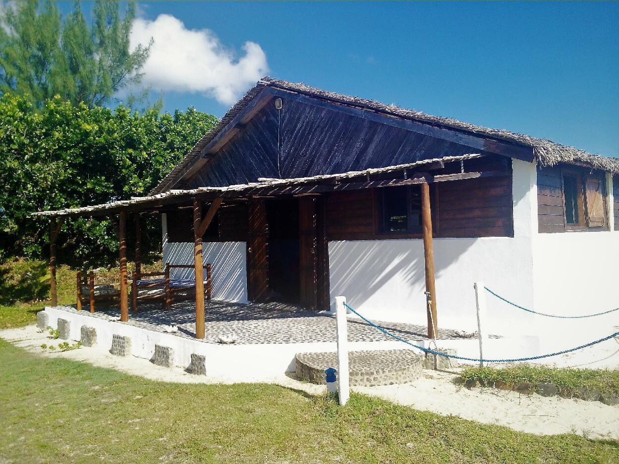 Een traditioneel houten huis met rieten dak, een overdekte veranda en een witte gevel.