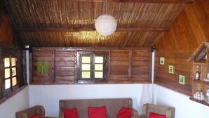 A cozy room with a wooden ceiling, a sofa set with red cushions, and a small table with books. - Comfort Villa with Sea View (Sainte-Marie)