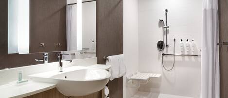 Un baño moderno con un lavabo grande, espejo, ducha e inodoro.