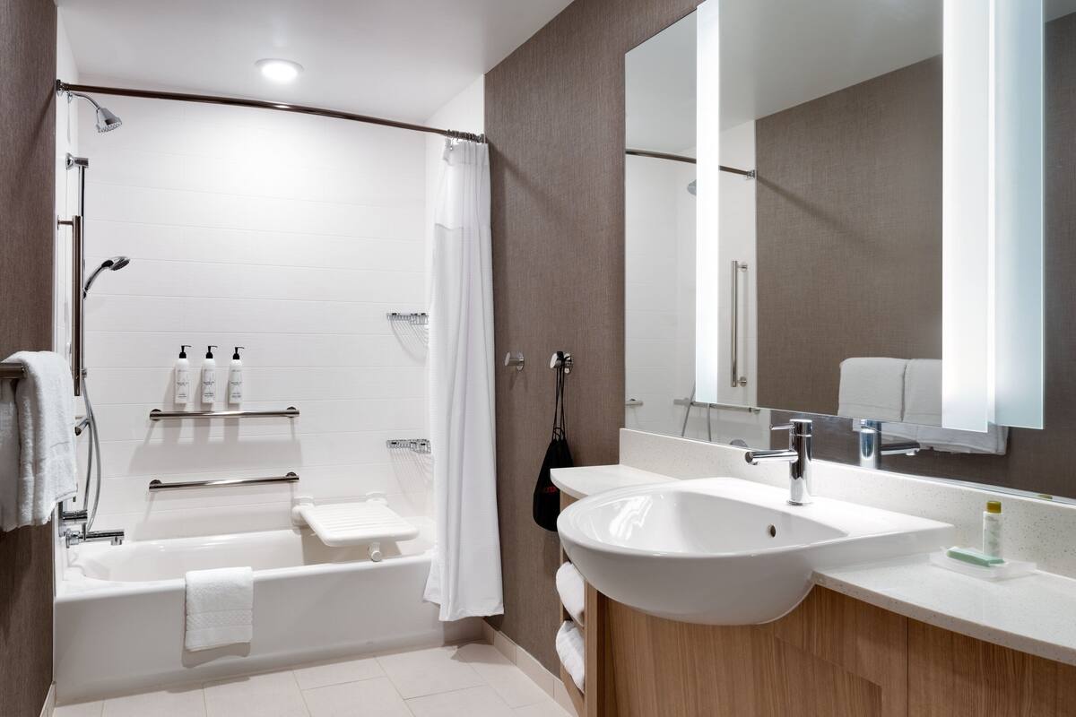 A modern bathroom with a bathtub, shower, and sink.