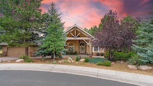 A two-story house with a gabled roof, a garage, and a well-maintained front yard with various plants and a driveway. - Lone Oak (Flagstaff)