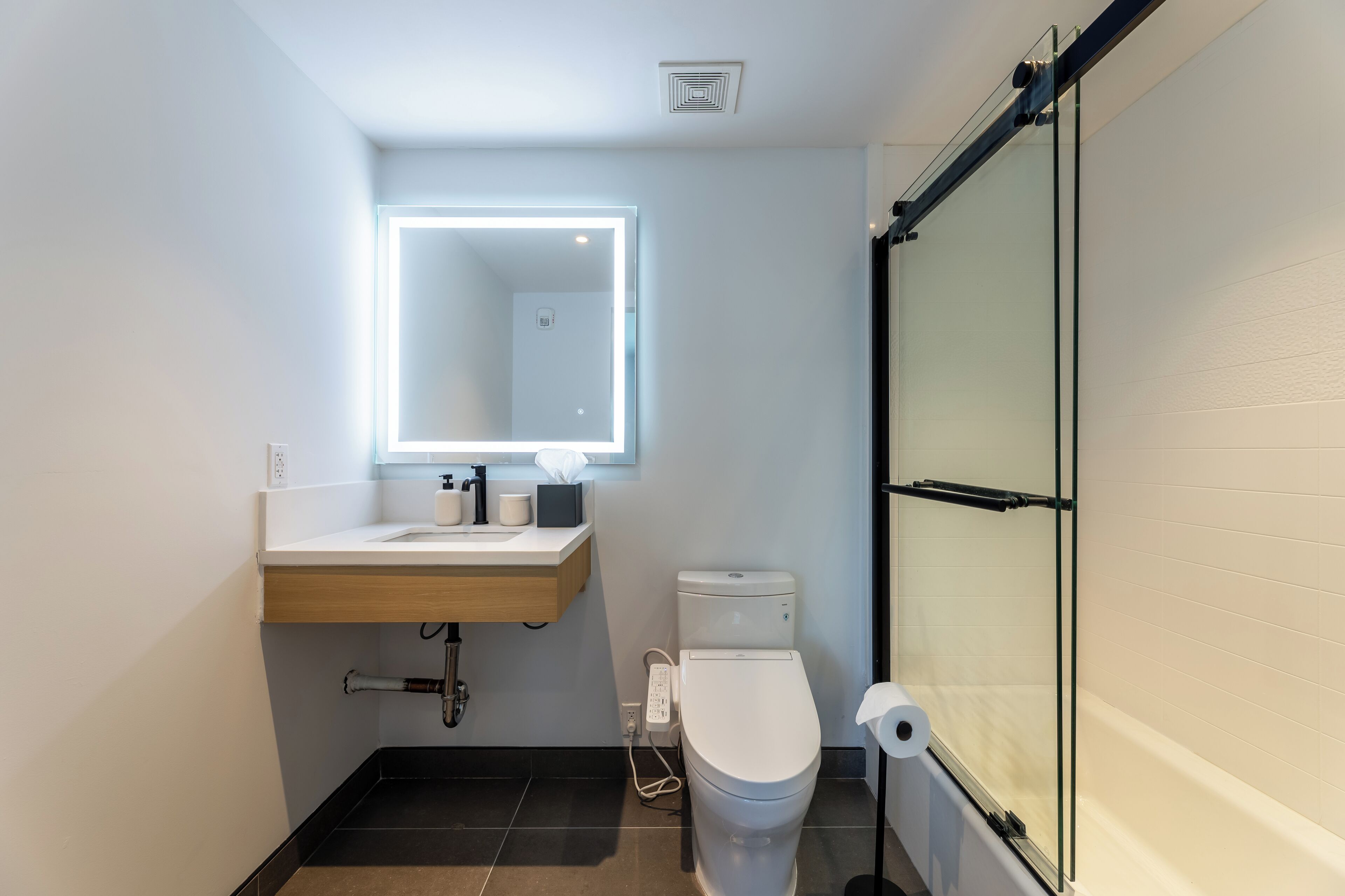 A modern bathroom with a white sink, a toilet, and a glass shower enclosure.