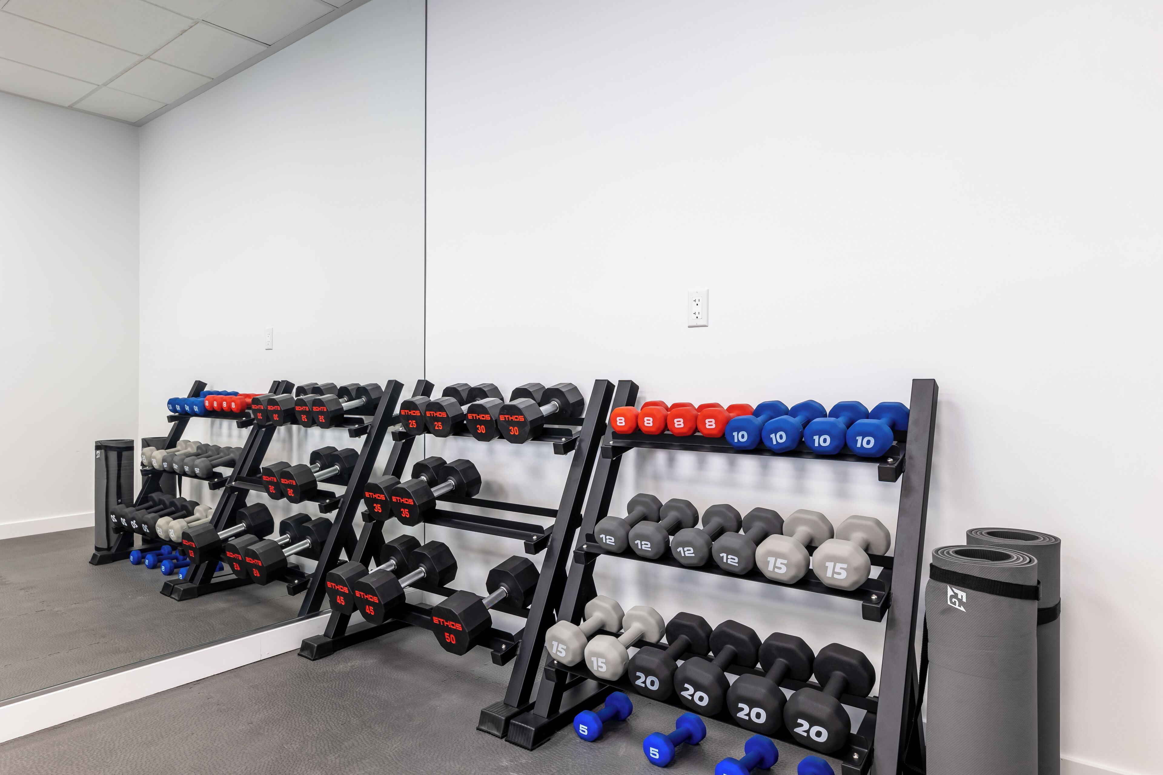 A gym with weight racks, dumbbells, and exercise mats.