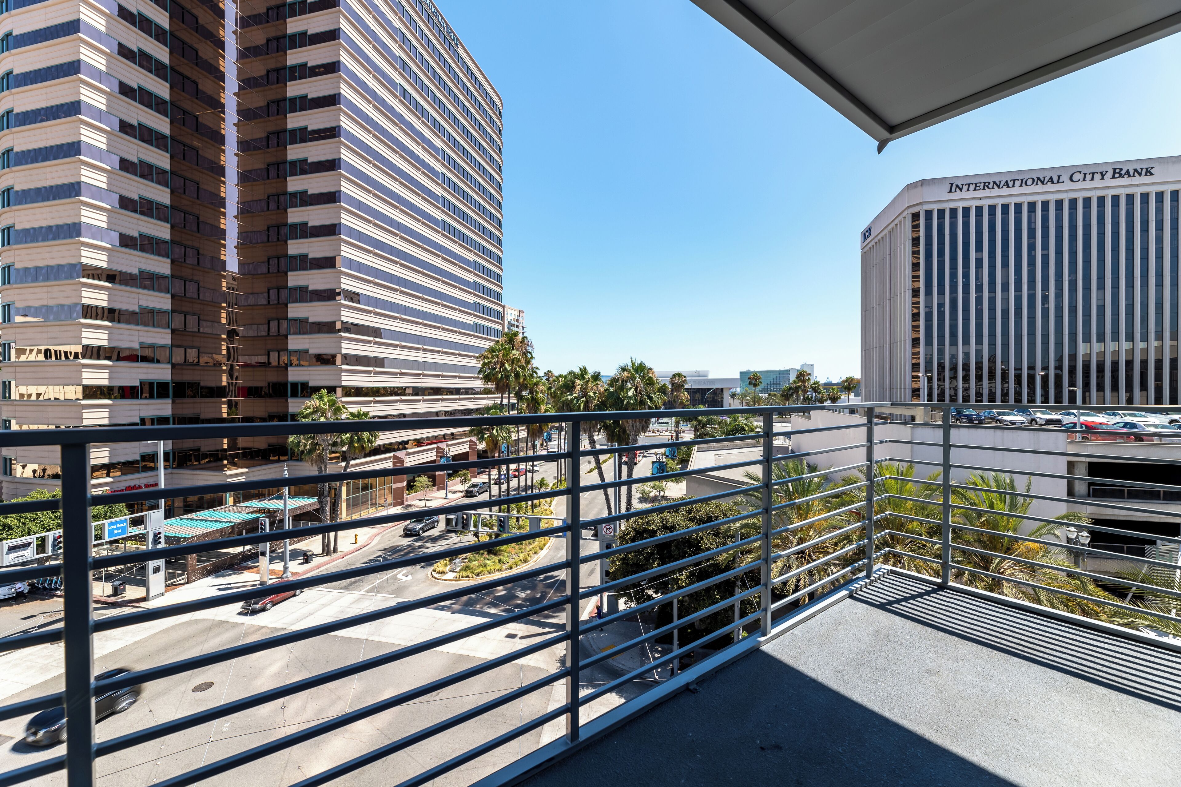A view from a balcony overlooking a parking area with a building labeled "International City Bank" in the background.