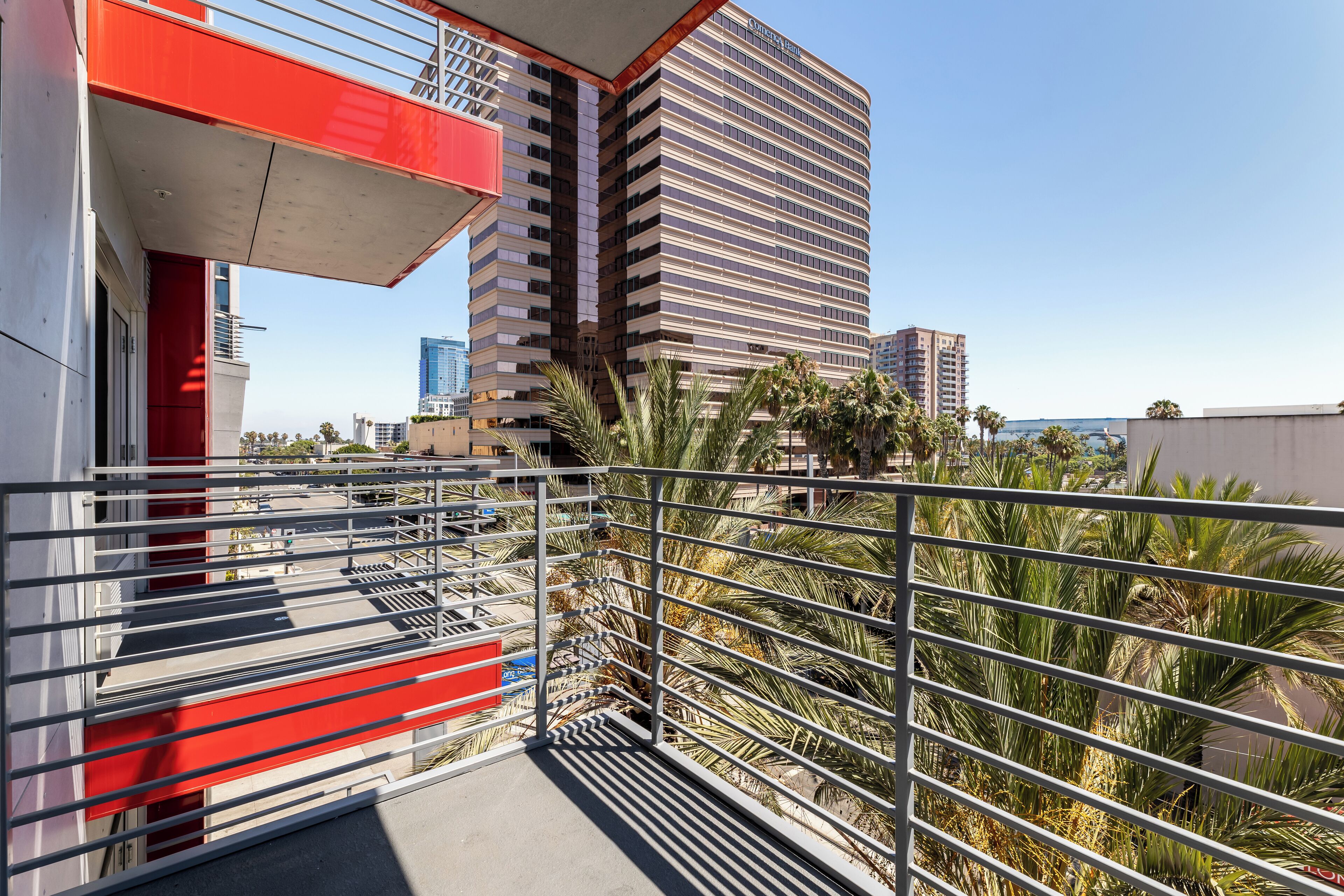 Un hotel moderno con facciata curva, esterno rosso e bianco e un balcone con ringhiere in metallo.