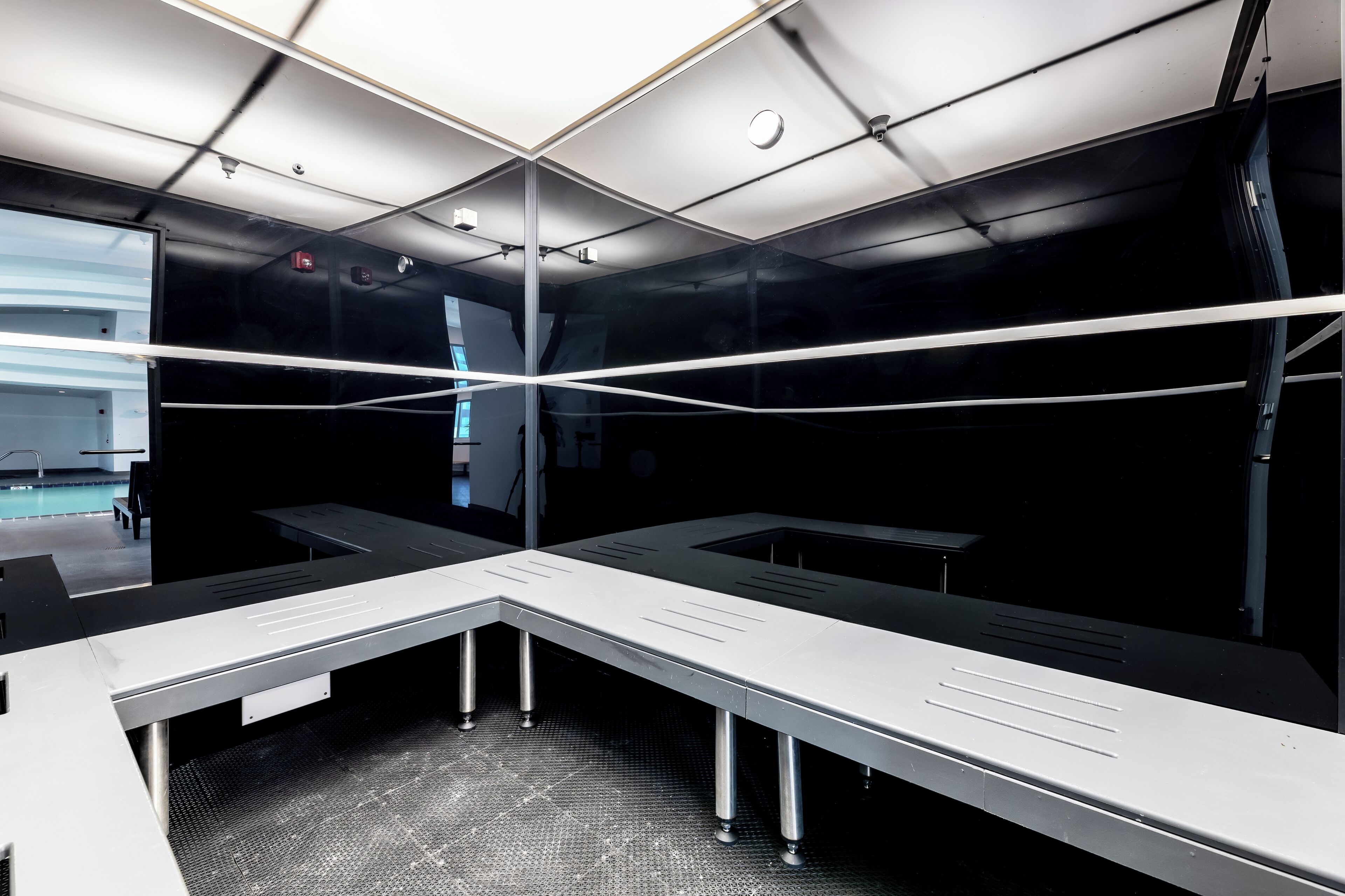 Una sala de conferencias moderna con un separador de vidrio, una mesa grande e iluminación empotrada en el techo.