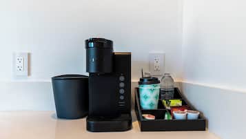A coffee maker, a trash bin, and a water bottle on a countertop.