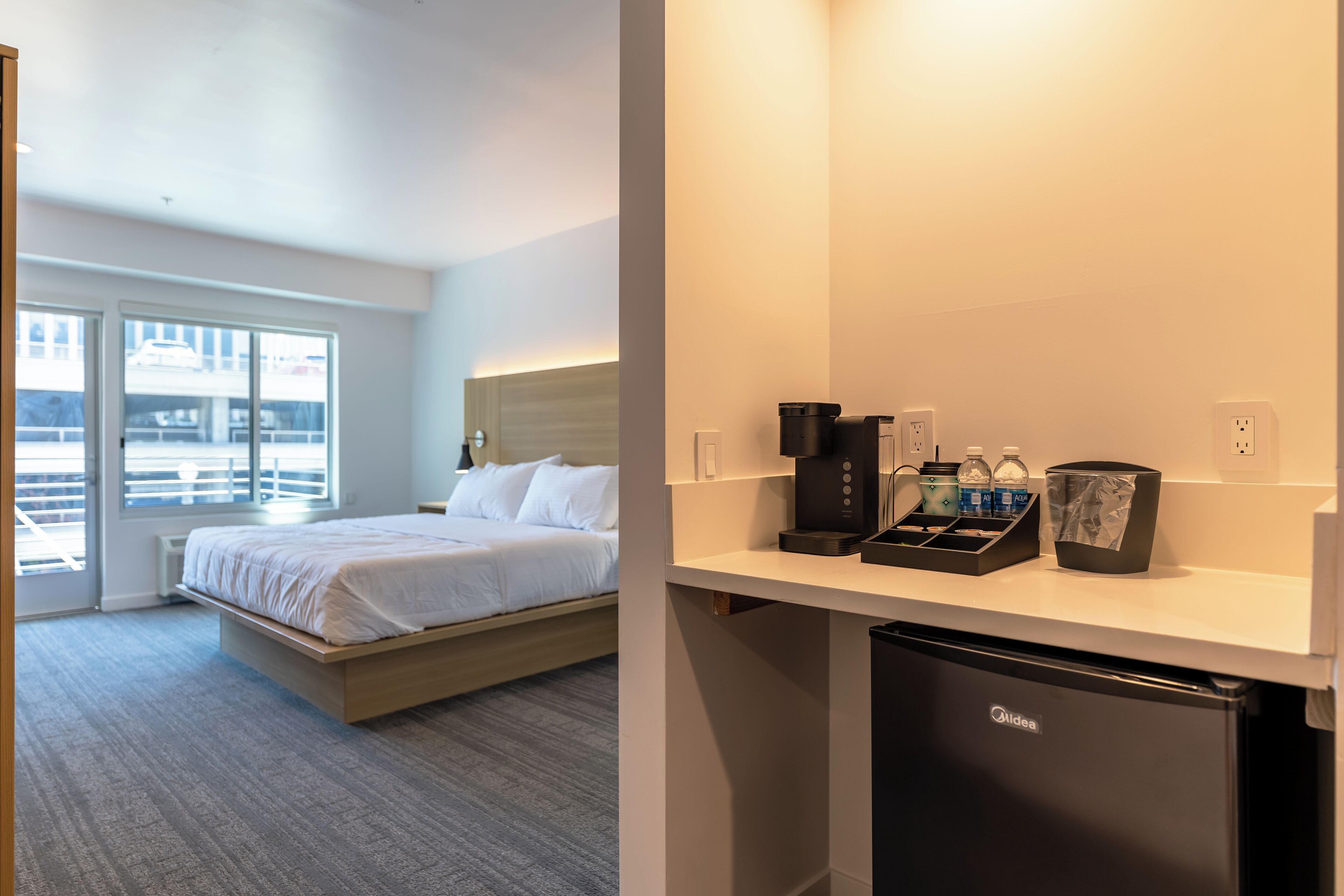 Ett hotellrum med en säng, ett skrivbord med en kaffemaskin och ett kylskåp.