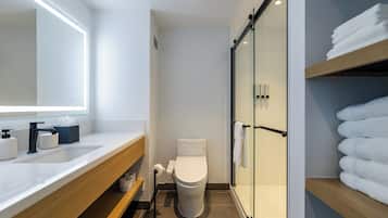 A modern bathroom with a white sink, a toilet, and a glass shower enclosure.